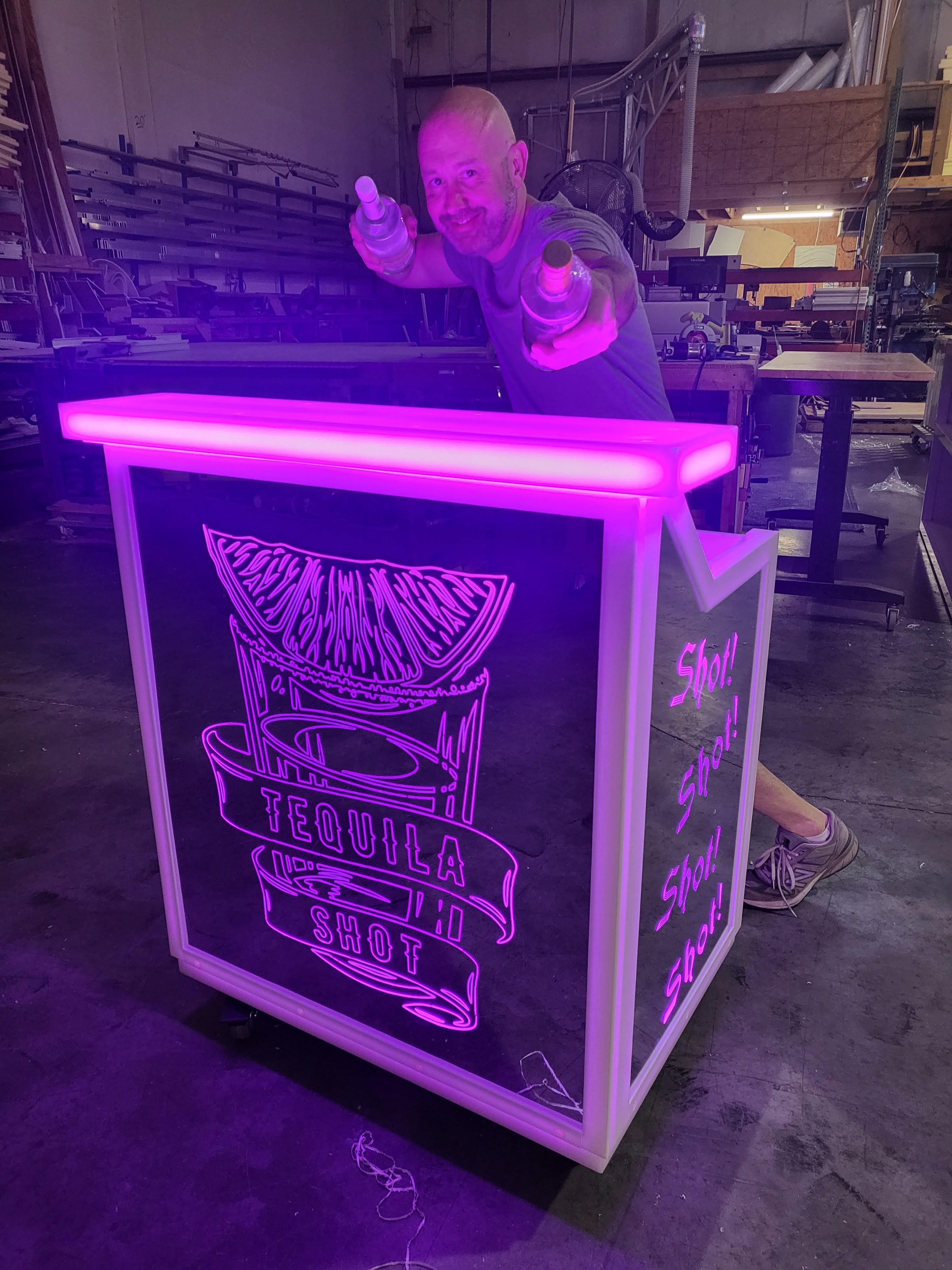 Man bartending behind pink LED cocktail bar 